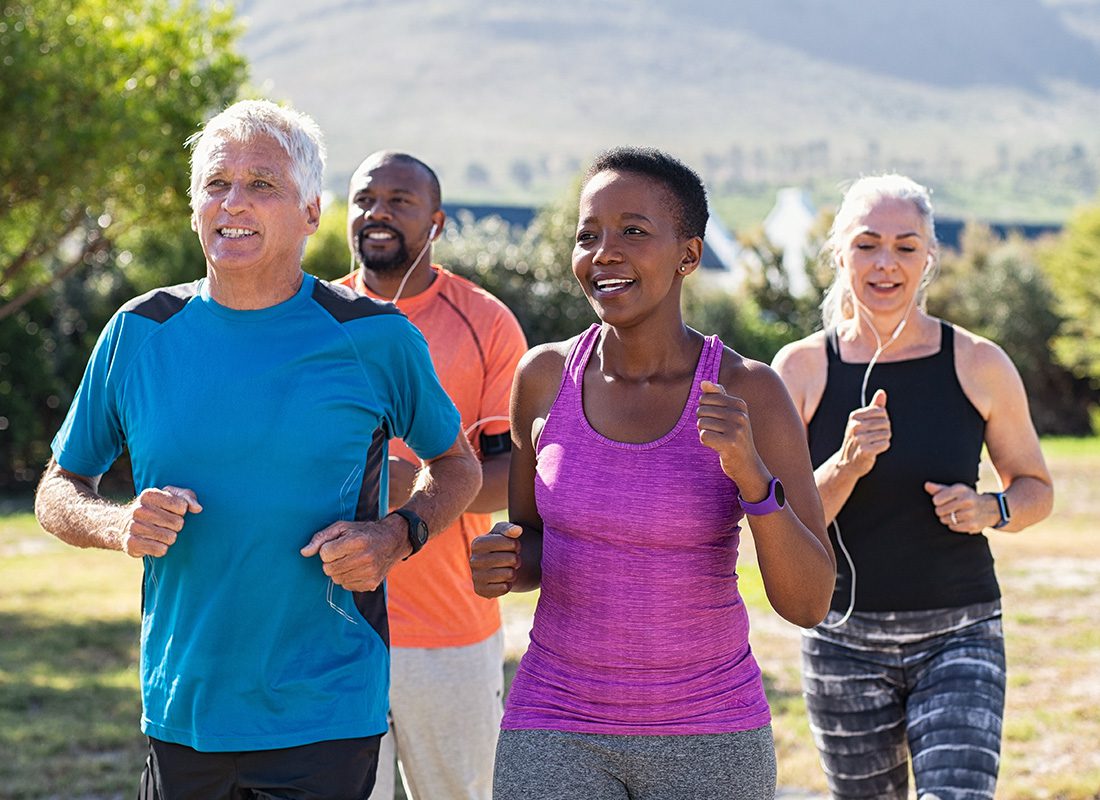 Employee Benefits - Group of Mature Adults Jogging Together at a Park During a Sunny Day